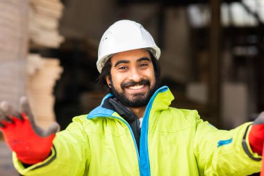 Depoda çalışan kasklı ve sakallı bir işçi.