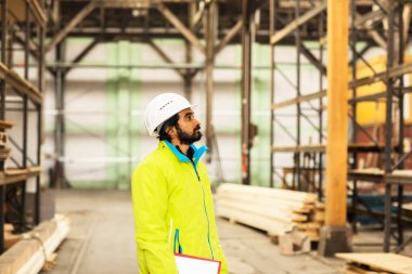 Depoda çalışan kasklı ve sakallı bir işçi.