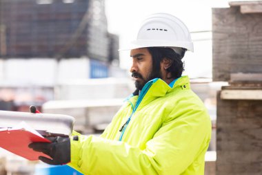 Dışarıda çalışan kasklı ve sakallı bir işçi.