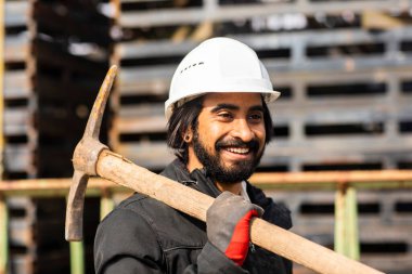 Dışarıda çalışan kasklı ve sakallı bir işçi.