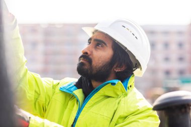 Dışarıda çalışan kasklı ve sakallı bir işçi.