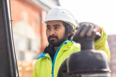 Dışarıda çalışan kasklı ve sakallı bir işçi.