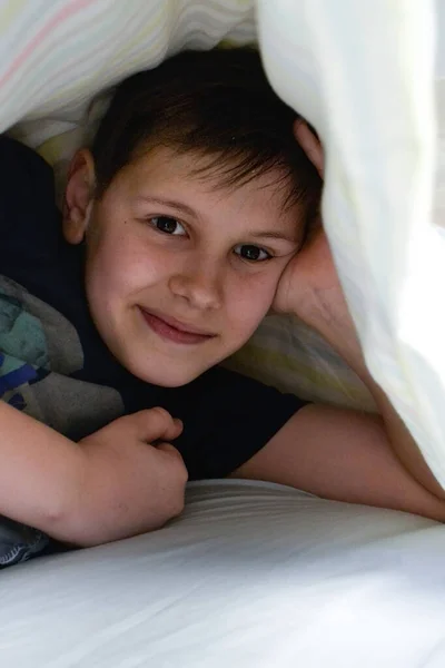 Χαμογελαστό Αγόρι Στο Κρεβάτι Του Κάτω Από Κουβέρτα — Φωτογραφία Αρχείου