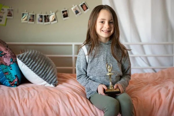 Linda Niña Sentada Una Cama Sosteniendo Trofeo — Foto de Stock