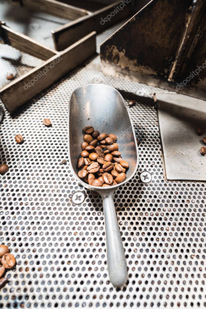 Coffee beans in metal spoon inside of a coffee roaster