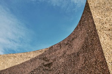 Şehirdeki bulutlu mavi gökyüzüne karşı anıt duvarının altından.