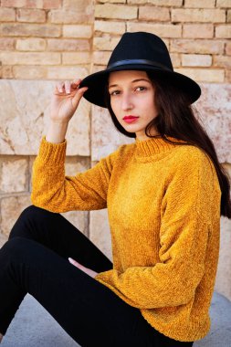 Şehirde bir bankta oturan gülümseyen genç bir esmerin portresi.