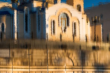 Sudaki dalgalı mimari bir binanın renk yansıması.