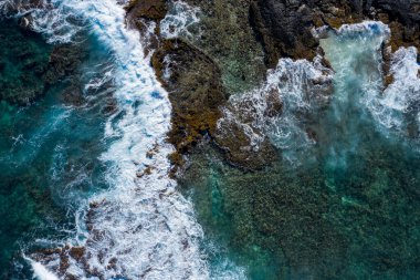 Hawaii 'deki kahverengi kayalara çarpan okyanus dalgalarının insansız hava aracı fotoğrafı.