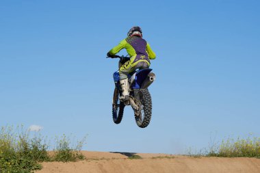 Motokrosta motosikletle gösteri yapan adamın yan görüntüsü
