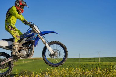 Motokrosta motosikletle gösteri yapan adamın yan görüntüsü