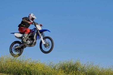 Motokrosta motosikletle gösteri yapan adamın yan görüntüsü