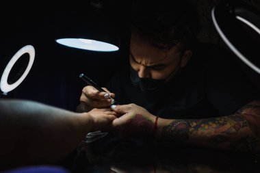 Manikürcü, müşterinin tırnaklarına reçine sürüyor.