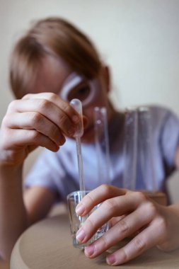 Gözlüklü bir kız evde kimyasal deneyler yapıyor.