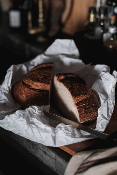 Bochník Čerstvého Křupavého Chleba Balicím Papíru Tmavé Kuchyni — Stock fotografie