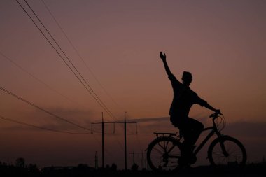 Gün batımında bisiklet süren bir kızın akşam yürüyüşü.