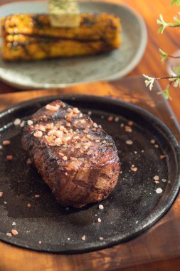 Ahşap masada ızgara biftek ve sarımsaklı mısır. Gurme yemekleri..