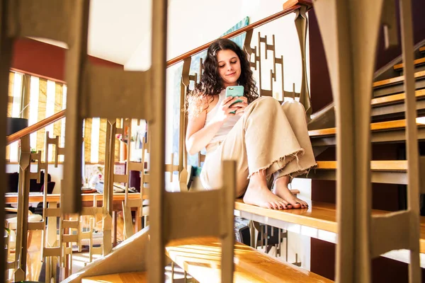 家の階段に座って携帯電話と話している若い女性は — ストック写真