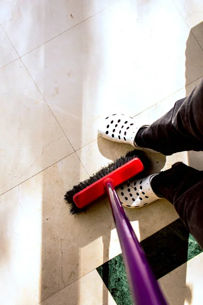 woman\'s feet with a broom sweeping the house