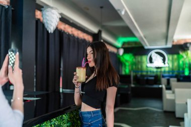 Güzel esmer kız hapsettikten sonra kokteyl içiyor.