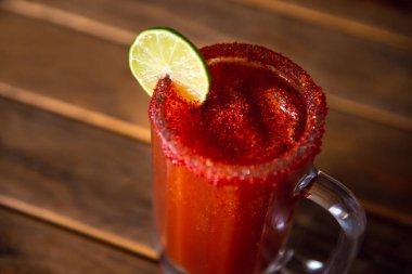 Michelada birası ve domates suyu. Tahta masada biralı Clamato..