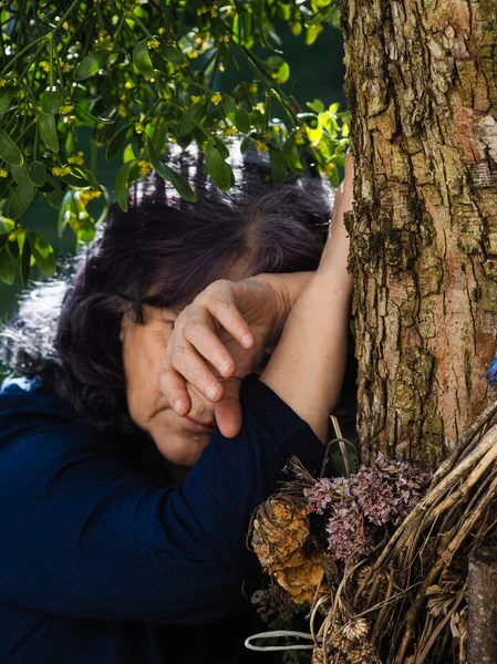 Senior adult woman near a loved tree and mistletoe plant