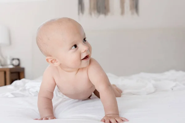 Bebek Beyaz Çarşaflarla Yatakta Sürünürken Yan Tarafa Bakıyor — Stok fotoğraf