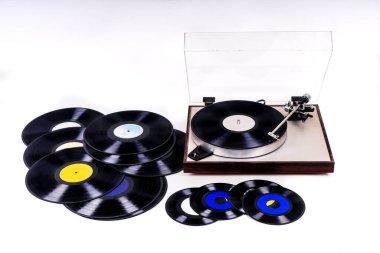 Beyaz arkaplandaki vinil plakların yanında kayıt cihazı var.