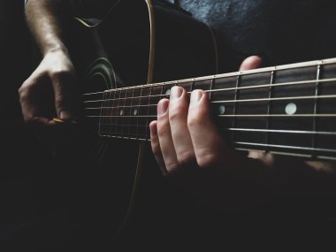 Adamın elleri akustik gitar çalıyor.