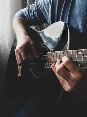 Adamın elleri akustik gitar çalıyor.