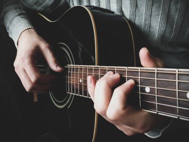 Adamın elleri akustik gitar çalıyor.
