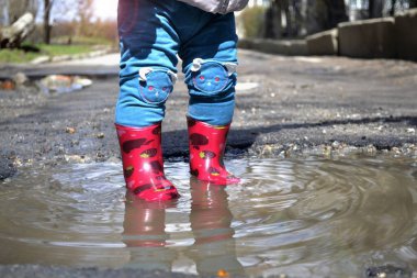 Çocuk su birikintisinde duruyor.