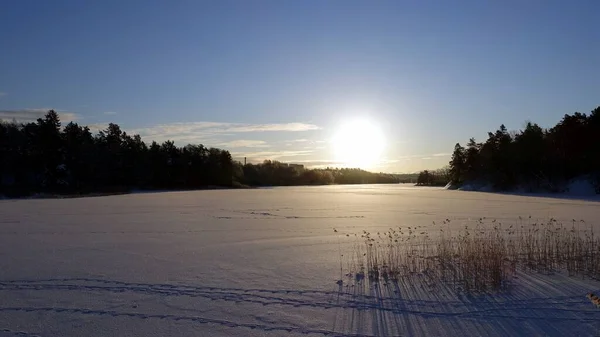 It is dawn and the sun has just risen over the frozen lake