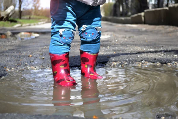 Çocuk su birikintisinde duruyor.