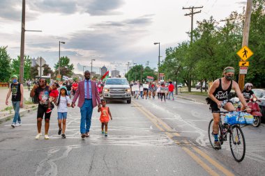 Bir anne ve baba protesto yürüyüşünde çocuklarına önderlik ediyor.
