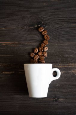 Siyah arka planda kahve çekirdekleri olan bir fincan.