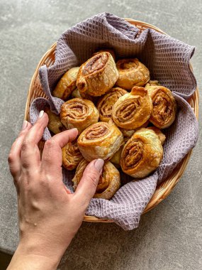 El, gri arka plandaki sepetten çörekleri alır.