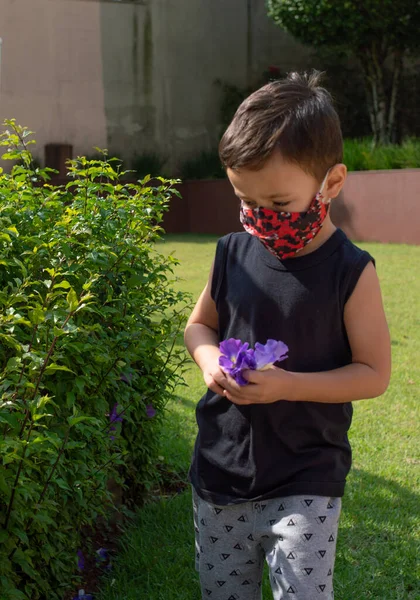 Çocuk Bahçede Pembe Bir Çiçek Ararken Maske Takıyor — Stok fotoğraf
