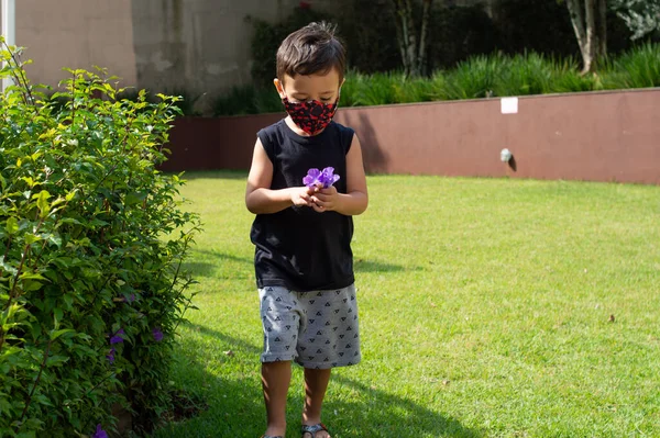Dziecko Chłopiec Pomocą Maski Ogrodzie Szuka Różowego Kwiatu — Zdjęcie stockowe