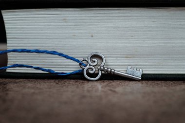 Kapalı kitaba mavi ipli gümüş anahtar