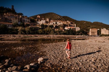 Kız Fransa 'nın güneyindeki kayalık nehir sahilinde yürüyor.