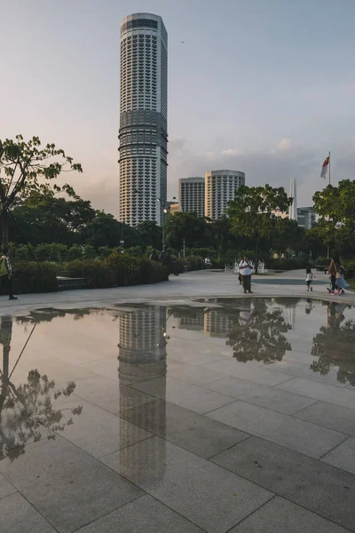 Modern Kerek Felhőkarcoló Szingapúr Belvárosában Tükröződik Egy Esőpocsolyában Naplementekor — Stock Fotó