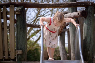 Young girl on the top of a slide watching down
