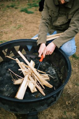 Çakmaklı bir adam arka bahçedeki şenlik ateşi için biraz ateş yakıyor.