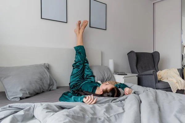 Молода Жінка Шовковій Піжамі Лежить Догори Ногами Ліжку Спальні Концепція — стокове фото