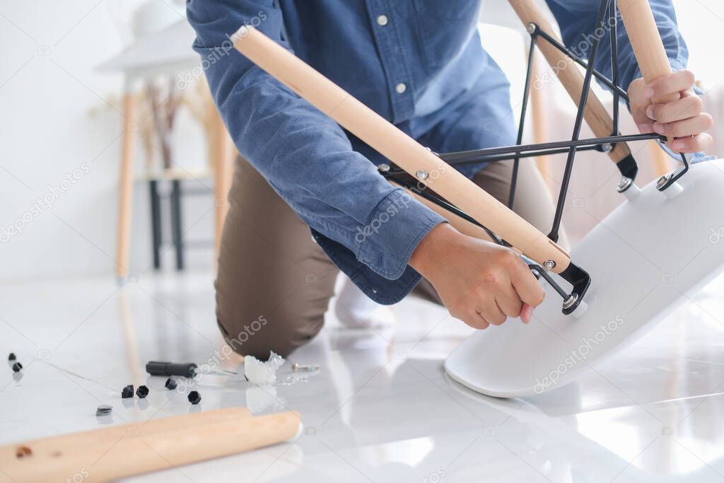 Young man doing DIY work, assembling furniture at home