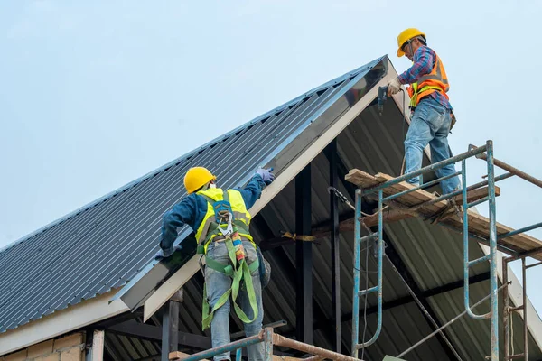 Roofer worker builder with hand drill installing new roof