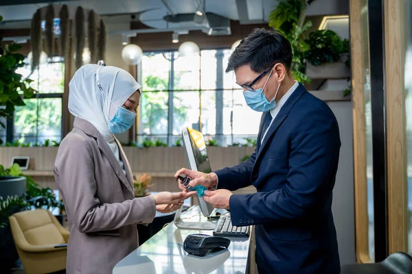 Business people with face mask are disinfecting hands to protect infection from coronavirus covid-19 before start working in office,Outbreak - Healthcare Concept.