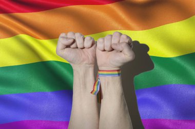 Gay adamın elleri yumruk ve LGTB bayrağı ve bileziği