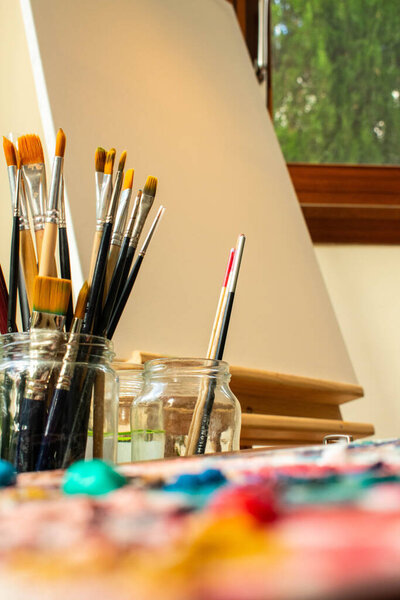 Чистые кисти в стеклянную банку и белый холст